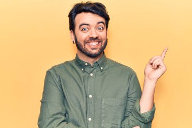 Gündelik kıyafetler giyen genç İspanyol adam gülümsüyor mutlu bir şekilde elini ve parmağını yana uzatıyordu. 
