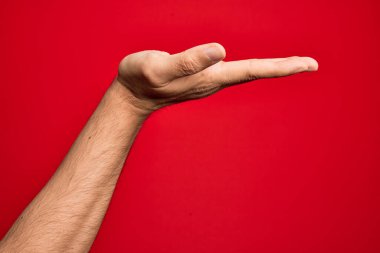 Avuç içi içi içi içi içi içi içi içi içi boş fotokopi alanı ile izole edilmiş kırmızı arka plan üzerinde parmaklarını gösteren beyaz bir gencin eli.