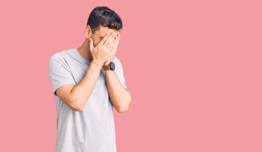 Ayılı yakışıklı genç adam, günlük tişörtler giyiyordu. Üzücü bir ifade takınıyordu. Ağlarken yüzünü ellerle kapatıyordu. depresyon kavramı. 