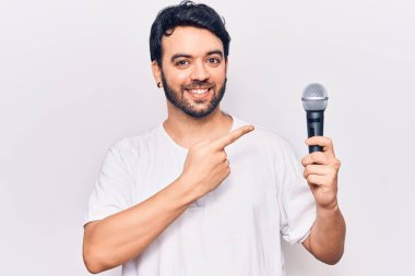 Genç İspanyol adam mikrofonla şarkı söylüyor. Gülümsüyor, mutlu bir şekilde işaret ediyor. 