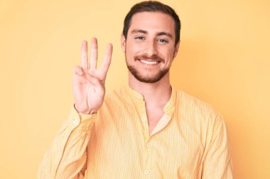 Gündelik kıyafetler giyen genç yakışıklı üç numarayı gösterip işaret ederken kendinden emin ve mutlu bir şekilde gülümsüyor.. 