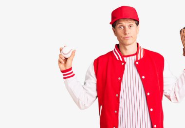 Beyzbol üniforması giyen yakışıklı bir genç. Golve topu tutuyor. Düşünme tavrı takınıyor. 