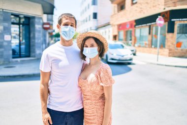 Tıbbi maske takan güzel bir çift şehrin caddesinde yürüyor.