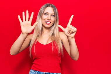 Genç sarışın kadın gündelik kıyafetler giyer ve yedinci parmaklarını göstererek gülümserken kendinden emin ve mutluydu.. 