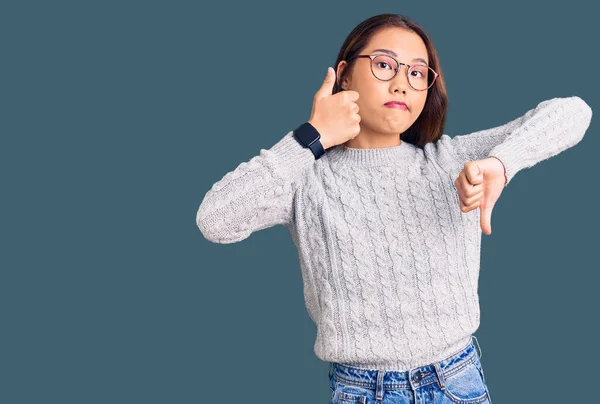 若い美しい中国の女の子が親指を上下に 意見の相違や合意の式を行うカジュアルな服を着て 狂気の葛藤 — ストック写真