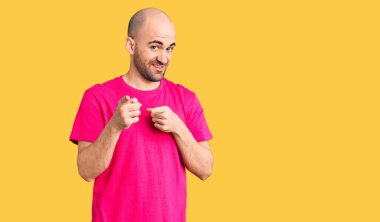 Sıradan tişörtler giyen genç yakışıklı adam mutlu ve komik yüzüyle kamerayı işaret ediyor. iyi enerji ve titreşimler. 