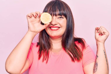 Genç ve cüsseli bir kadın limon tutarak gururla bağırıyor zaferi kutluyor ve başarıyı kollarını kaldırarak kutluyor. 