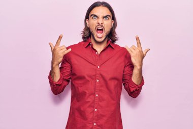 İş kıyafetleri giymiş, çılgın bir ifadeyle bağıran genç yakışıklı adam elleri havada rock sembolü yapıyor. Müzik yıldızı. ağır kavram. 