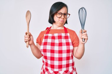 Esmer kadın, aşçı fırçası ve kaşıkla aşçılık yapıyor. Kuşkucu ve gergin. Sorunları yüzünden surat asıyor. negatif kişi. 