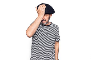 Orta yaşlı, çizgili tişört giyen ve beyaz arka planda Fransız beresi takan yakışıklı bir adam. Unuttum, kötü hafıza konsepti.