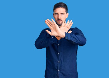 Genç yakışıklı bir adam gömleğini giyiyor. Reddedilmiş yüz ifadesi. Kollarını kavuşturuyor. 