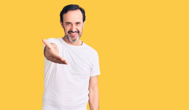 Orta yaşlı, yakışıklı, sıradan tişörtler giyen, neşeli gülümseyen, yardım eli uzatan ve kabul gören bir adam.. 