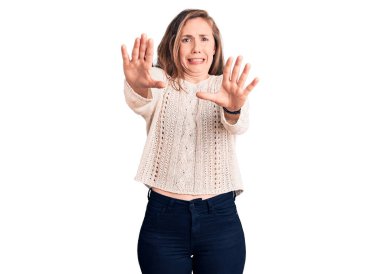 Genç ve güzel sarışın kadın, günlük süveter giyiyor. Korkudan ödü patlıyor ve korkuyor. El hareketlerini durdur, şok içinde bağır. panik konsepti. 