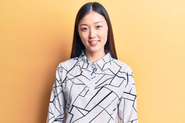 Genç, güzel Çinli bir kadın zarif bir gömlek giyiyor ve yüzünde mutlu ve havalı bir gülümseme var. şanslı kişi. 