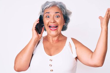 Son sınıf İspanyol beyaz saçlı kadın akıllı telefonda konuşuyor zaferi mutlu bir gülümsemeyle kutluyorlar ve kazanan ifade ellerini kaldırıyor. 