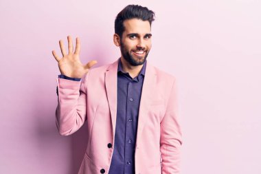 Sakallı, zarif ceketli, beş numaralı parmaklarıyla gösteriş yapan yakışıklı bir genç. Kendinden emin ve mutlu gülümsüyor.. 