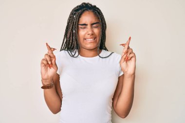 Saçları örgülü, beyaz tişörtlü, umut ve gözlerin kapalı bir şekilde gülümseyen genç Afro-Amerikalı bir kadın. Şans ve batıl inançlar. 