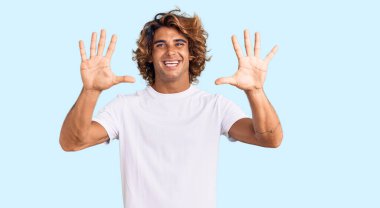 Günlük beyaz tişört giyen genç İspanyol adam on numarayı gösterip işaret ederken kendinden emin ve mutlu gülümsüyor.. 