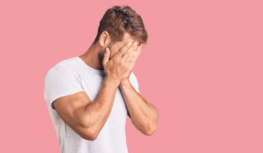 Beyaz günlük beyaz tişört giyen, suratını ellerle örten ve ağlayan genç beyaz bir adam. depresyon kavramı. 