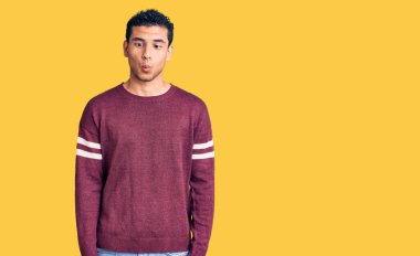 Hispanik yakışıklı genç adam gündelik kıyafetler giyip dudaklarıyla balık suratı yapıyor, çılgınca ve komik jestler yapıyor. Komik ifade. 