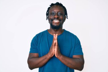 Saçları örgülü genç Afro-Amerikan bir adam. Elleriyle dua ediyor. Affedilmeyi diliyor.. 
