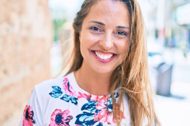 Genç İspanyol kadın gülümseyerek şehirde mutlu mesut duruyor.