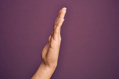İzole edilmiş mor arka planda parmaklarını gösteren beyaz bir gencin eli uzatılmış el hareketlerini gösteriyor.