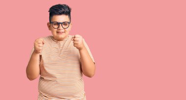 Sıradan kıyafetler ve gözlük takan küçük çocuk başarı için heyecanlanıyor kolları havada ve gözleri kapalı zaferi kutluyor. Kazanan konsept. 