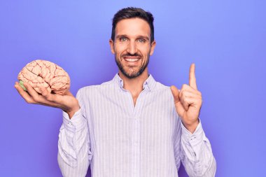 Genç ve yakışıklı bir adam hafızasını geri istiyor. Beyni soyutlanmış mor arka planda tutuyor. Gülümsüyor, mutlu bir şekilde elini ve parmağını yana uzatıyor.