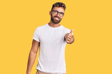 Gündelik giysiler ve gözlük takan genç İspanyol adam gülümseyen, yardım eli uzatan ve kabul gören biri.. 