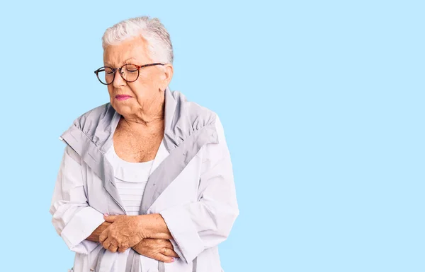 Senior beautiful woman with blue eyes and grey hair wearing casual clothes and glasses with hand on stomach because nausea, painful disease feeling unwell. ache concept.