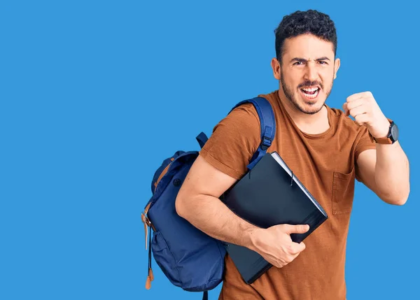 Joven Hombre Hispano Usando Mochila Estudiantil Sosteniendo Aglutinante Molesto Frustrado —  Fotos de Stock