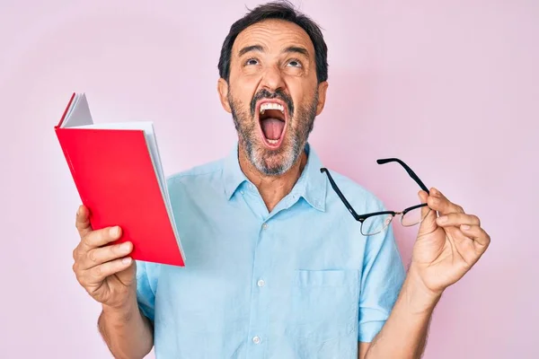 Hombre Hispano Mediana Edad Leyendo Libro Sosteniendo Gafas Enojado Loco —  Fotos de Stock