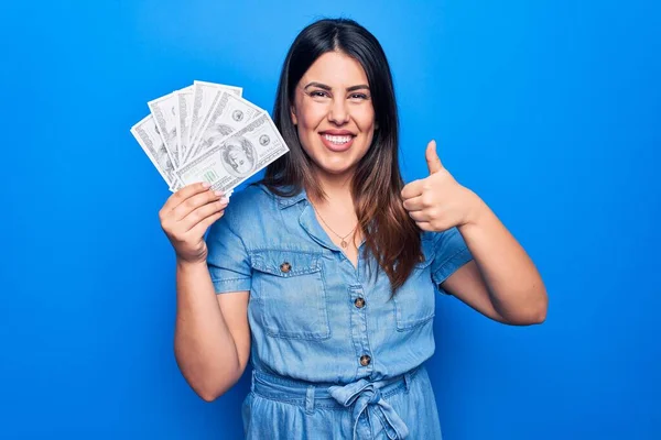 Güzel Esmer Bir Kadın Elinde Dolarlarla Mavi Arka Planda Mutlu — Stok fotoğraf