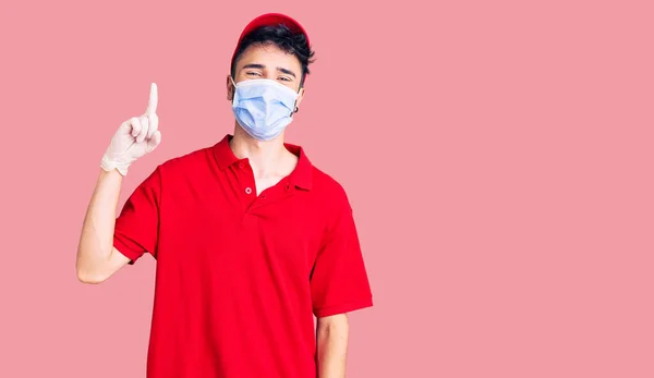 Young Hispanic Man Wearing Delivery Uniform Medical Mask Pointing Finger — Stock Photo, Image