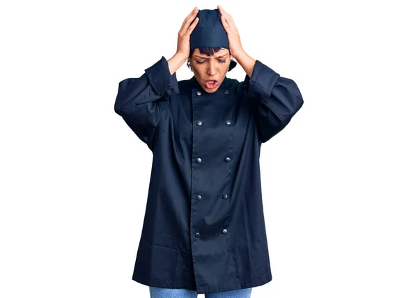 年轻的黑发女人穿着职业厨师的制服 因为疼痛和偏头痛而极度头痛和紧张 手放在头上 — 图库照片