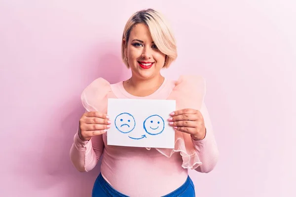 Young blonde plus size woman asking for positive change holding paper with emotion message looking positive and happy standing and smiling with a confident smile showing teeth