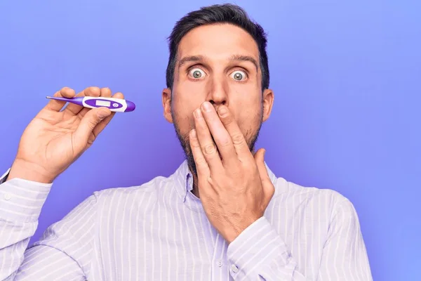 Homem Bonito Jovem Controlando Temperatura Segurando Termômetro Sobre Fundo Roxo — Fotografia de Stock