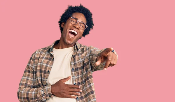 アフロの髪をしたハンサムなアフリカ系アメリカ人男性は カジュアルな服と眼鏡を身に着けて笑い 手でカメラに指を向けて体 恥の表情 — ストック写真