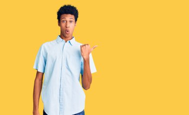 Gündelik giysiler giymiş genç Afro-Amerikan bir adam elleri yandan işaret ederek şaşırdı, ağzı açık hayret içinde kaldı.. 