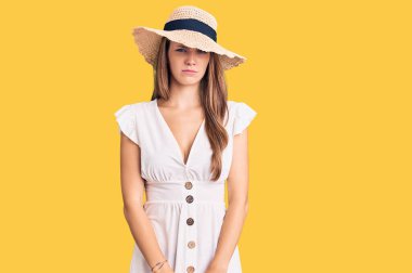 Yazlık elbise giyen, şapkalı, kuşkucu ve gergin genç, güzel sarışın bir kadın sorun yüzünden üzgün. negatif kişi. 