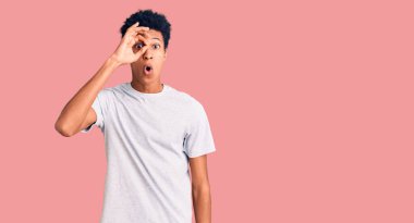 Genç Afro-Amerikan bir adam günlük giysiler giyiyor. Şaşırmış yüz ifadesiyle şaşırmış, parmaklarının arasından bakıyor. İnançsız ifade. 