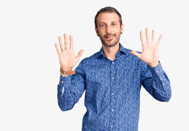 Genç ve yakışıklı bir adam günlük kıyafetler giyer ve 10 numarayı göstererek gülümserken kendinden emin ve mutluydu.. 