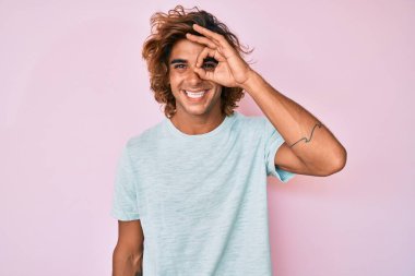 Gündelik kıyafetler giyen genç İspanyol adam el hareketleriyle gülümsüyor ve mutlu yüzüyle parmaklarından bakıyor.. 