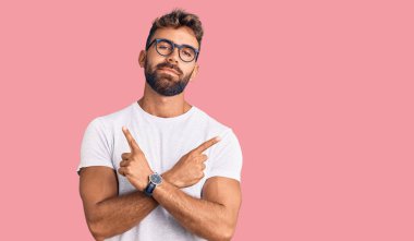 Gündelik kıyafetler giyen ve gözlük takan genç İspanyol adam her iki tarafı da parmaklarıyla işaret ediyor. Farklı yönlere. 