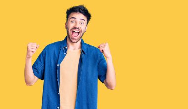 Gündelik giysiler giyen genç İspanyol adam şaşkınlık ve şaşkınlık içinde kollarını kaldırarak ve gözlerini açarak başarıyı kutluyor. Kazanan konsept. 