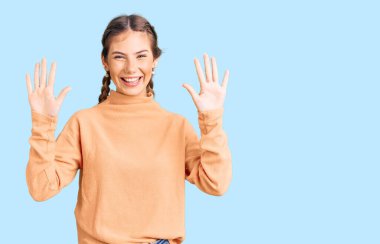 Sarışın, güzel, beyaz bir kadın. Kış süveteri giyiyor. 10 numaralı parmaklarıyla onu gösterip gülümsüyor.. 