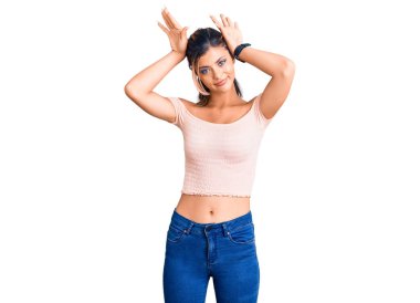 Gündelik kıyafetler giyen, tavşan kulağı yapan, avuçlarında alaycı ve şüpheci bakışlarla el hareketi yapan genç ve güzel bir kadın. Paskalya tavşanı konsepti. 