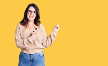 Güzel, genç, esmer bir kadın. Günlük kıyafetler ve gözlük takıyor. Gülümsüyor ve kameraya bakıyor.. 