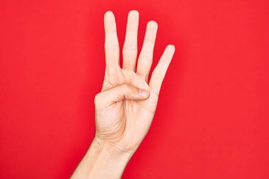 Kafkas genci parmaklarını izole edilmiş kırmızı arka planda gösteriyor. 4 numara 4 parmağı gösteriyor.